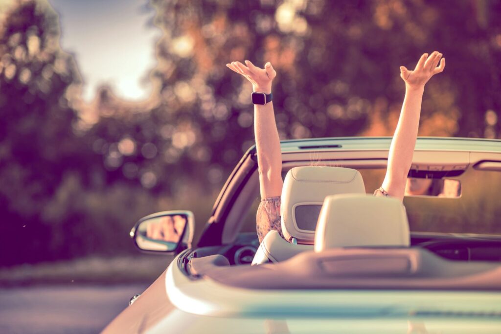 happy person with hands in air in car
