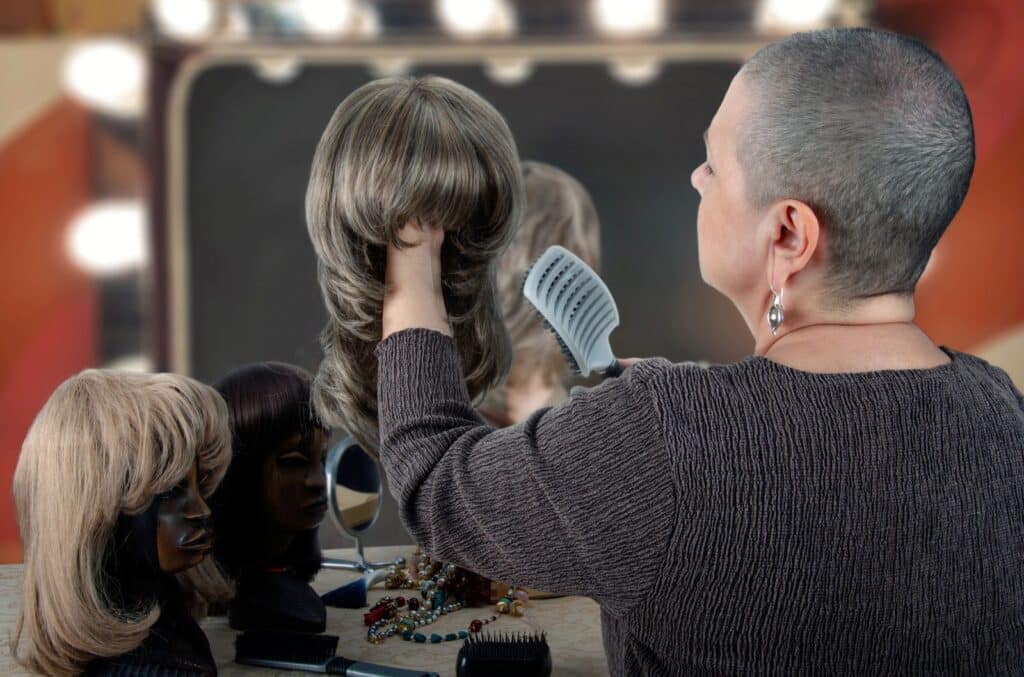 person with shaved head brushing wig