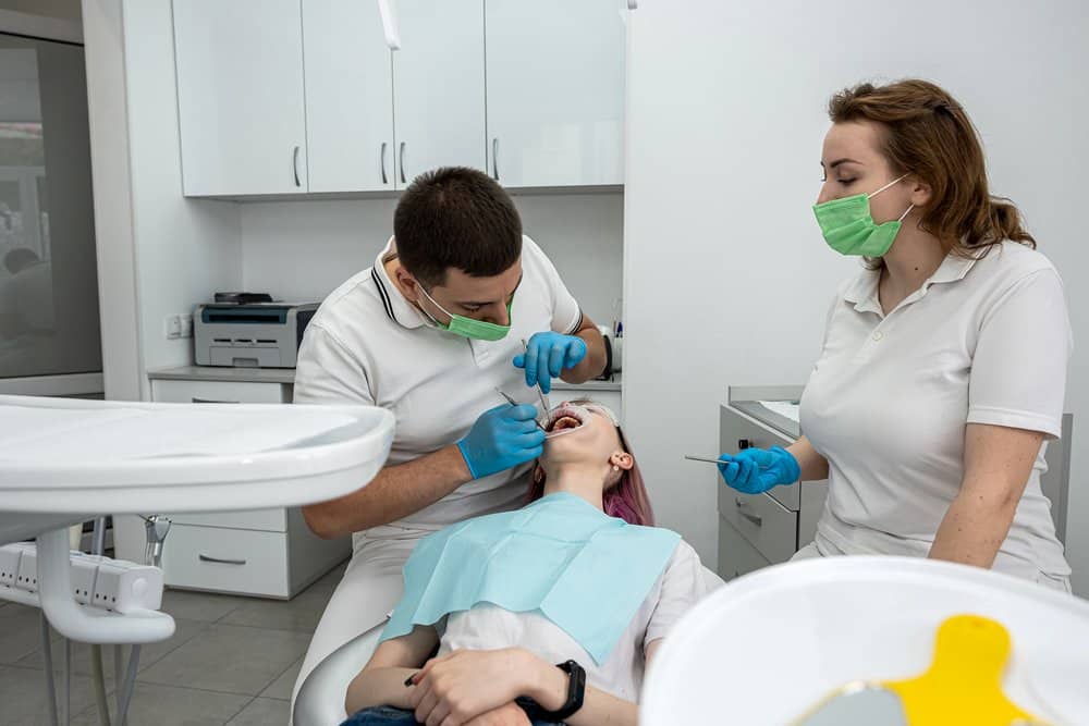 A dentist treats a patient with the assistance of a dental nurse in a modern clinic.