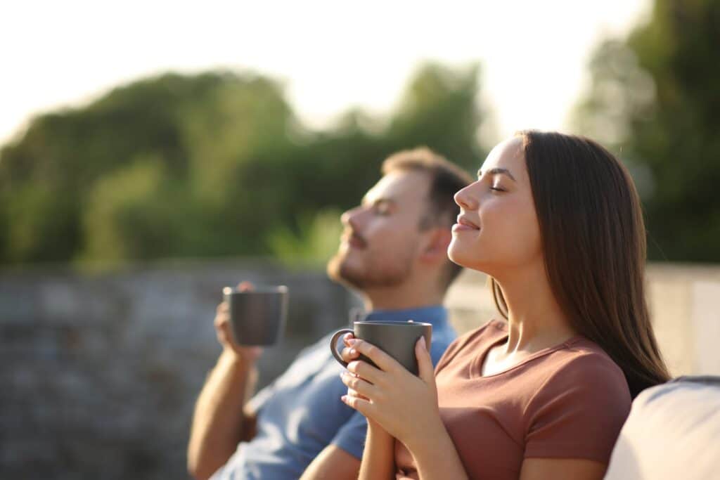 two happy people drinking coffee outside
