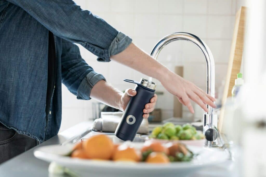 person filling up water bottle
