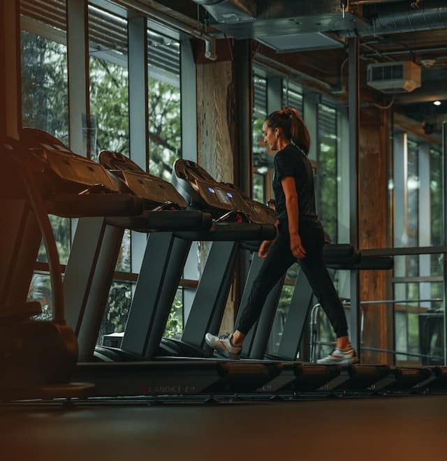 Woman walking on treadmill in gym to help treat PCOS