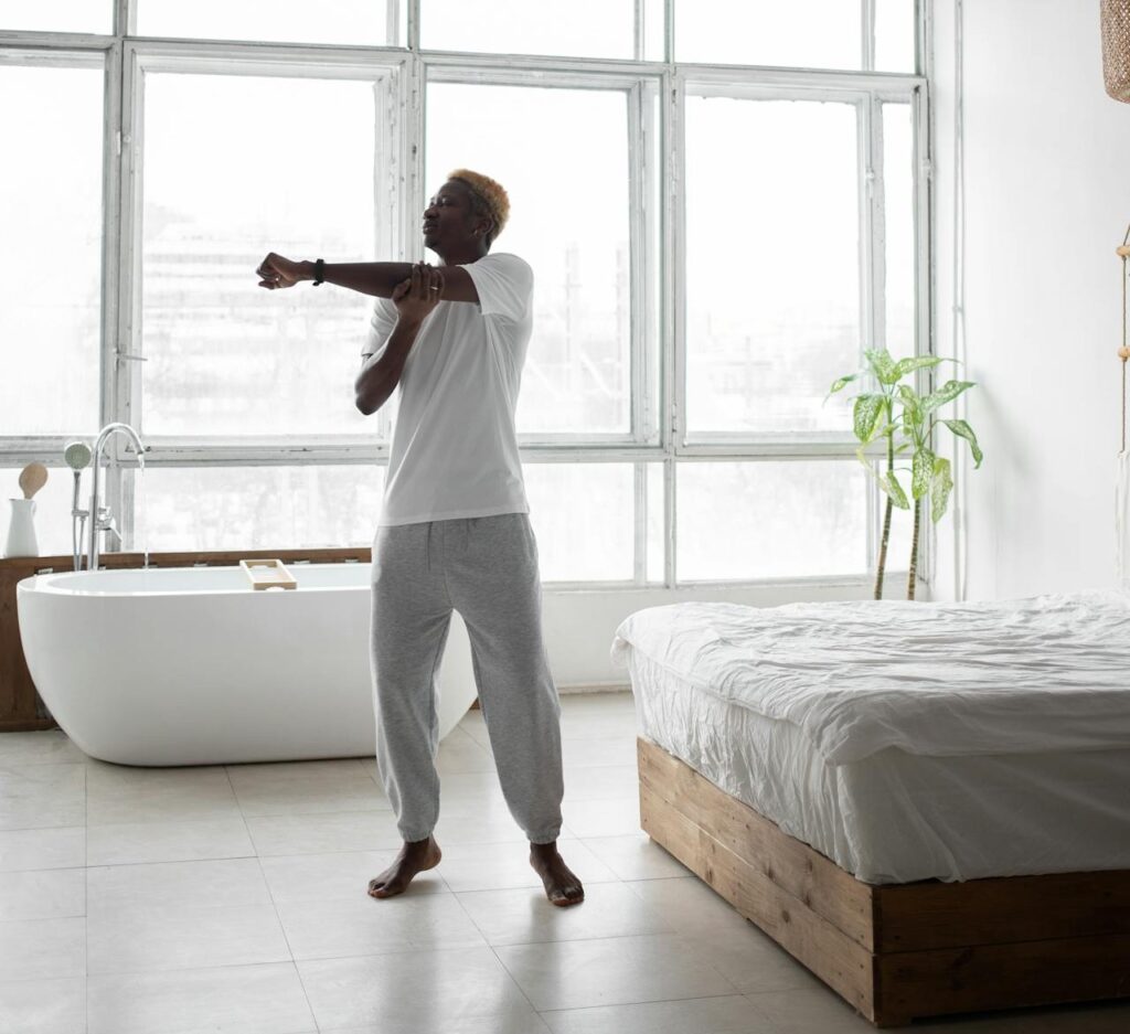 Man doing a forearm stretch next to his bed. 