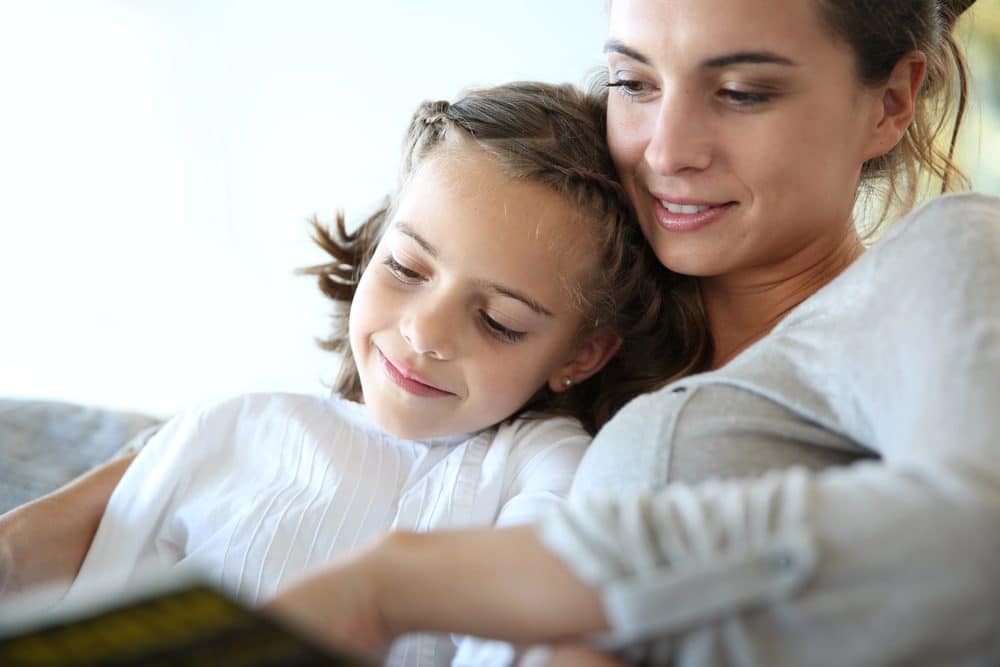A mother and daughter reading together at home, representing the growing trend of solo parenting in New Zealand in 2025.