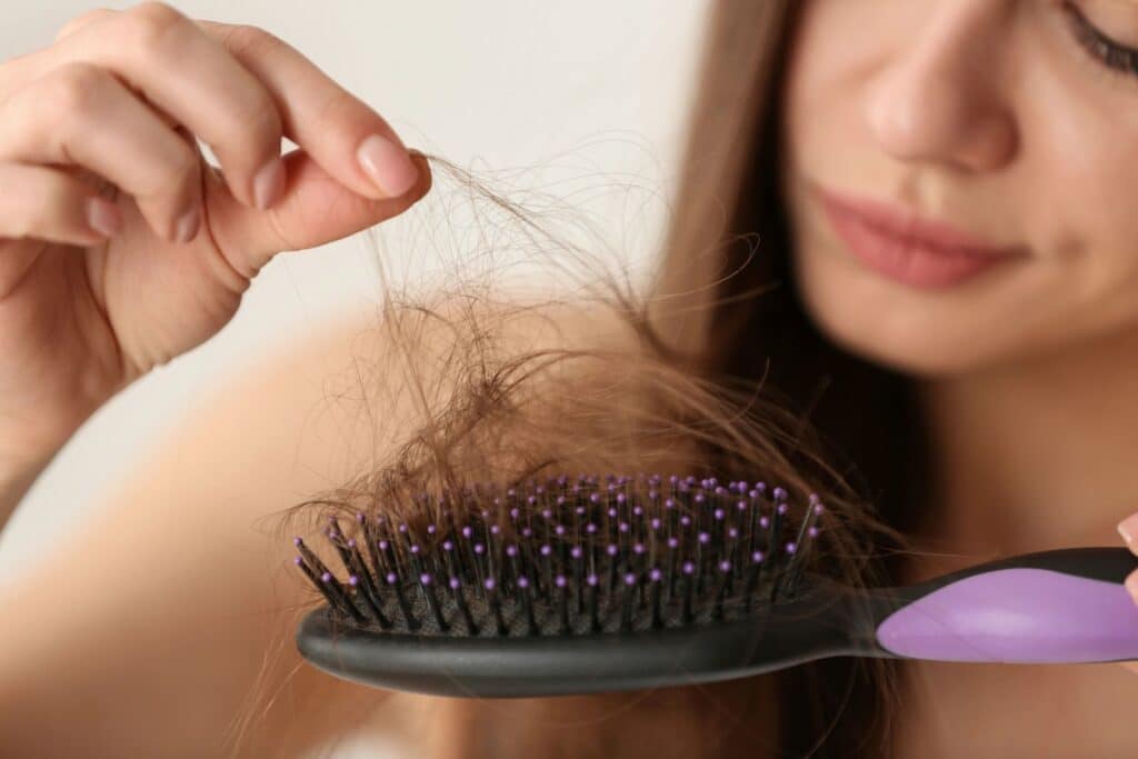 woman holding hair brush with hair loss
