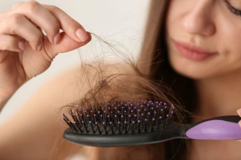 woman holding hair brush with hair loss