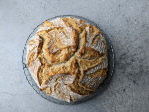 Freshly baked Irish soda bread loaf cooling on a metal wire rack.